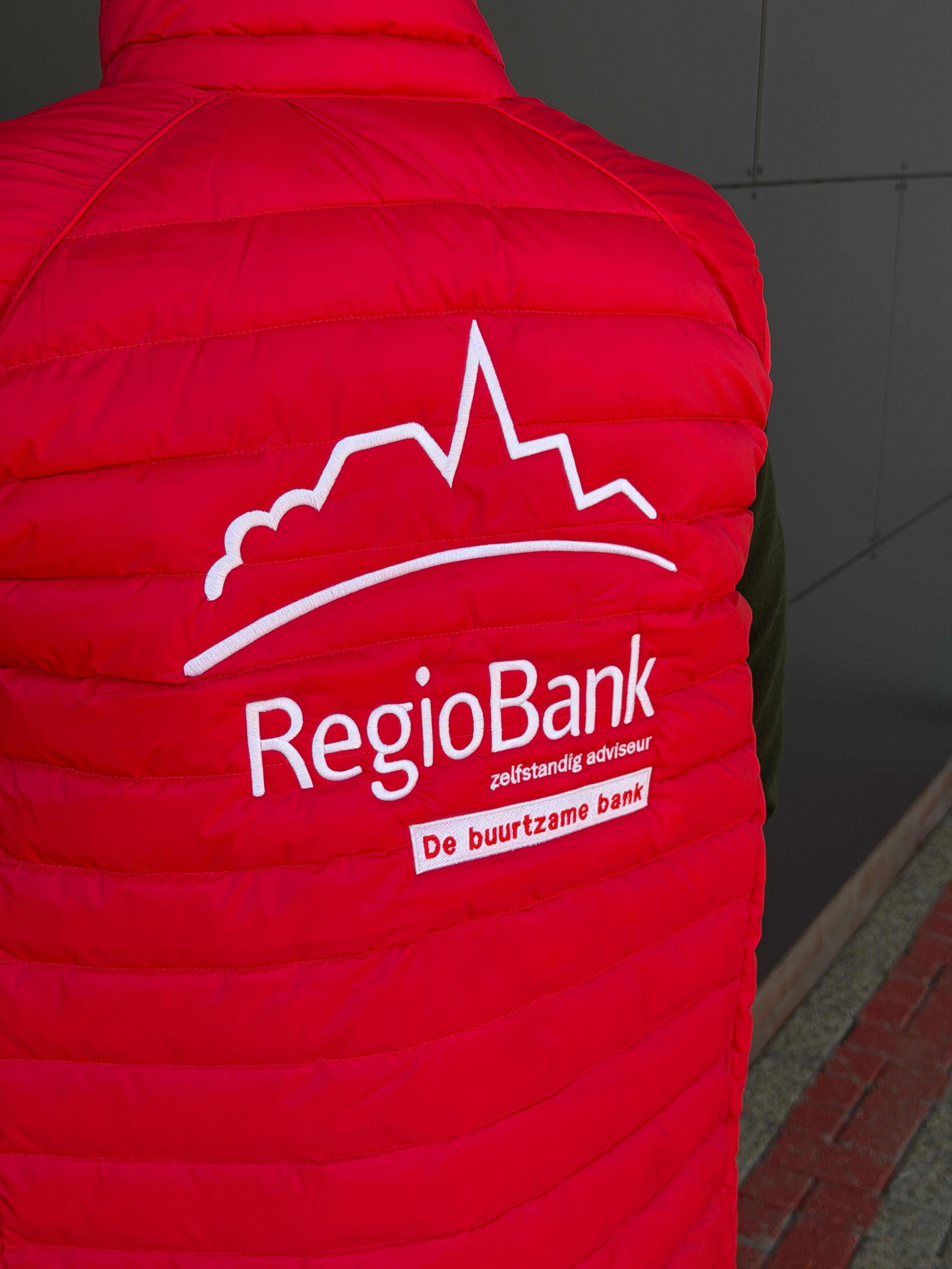 Rode bodywarmer met geborduurd bedrijfslogo op de rug